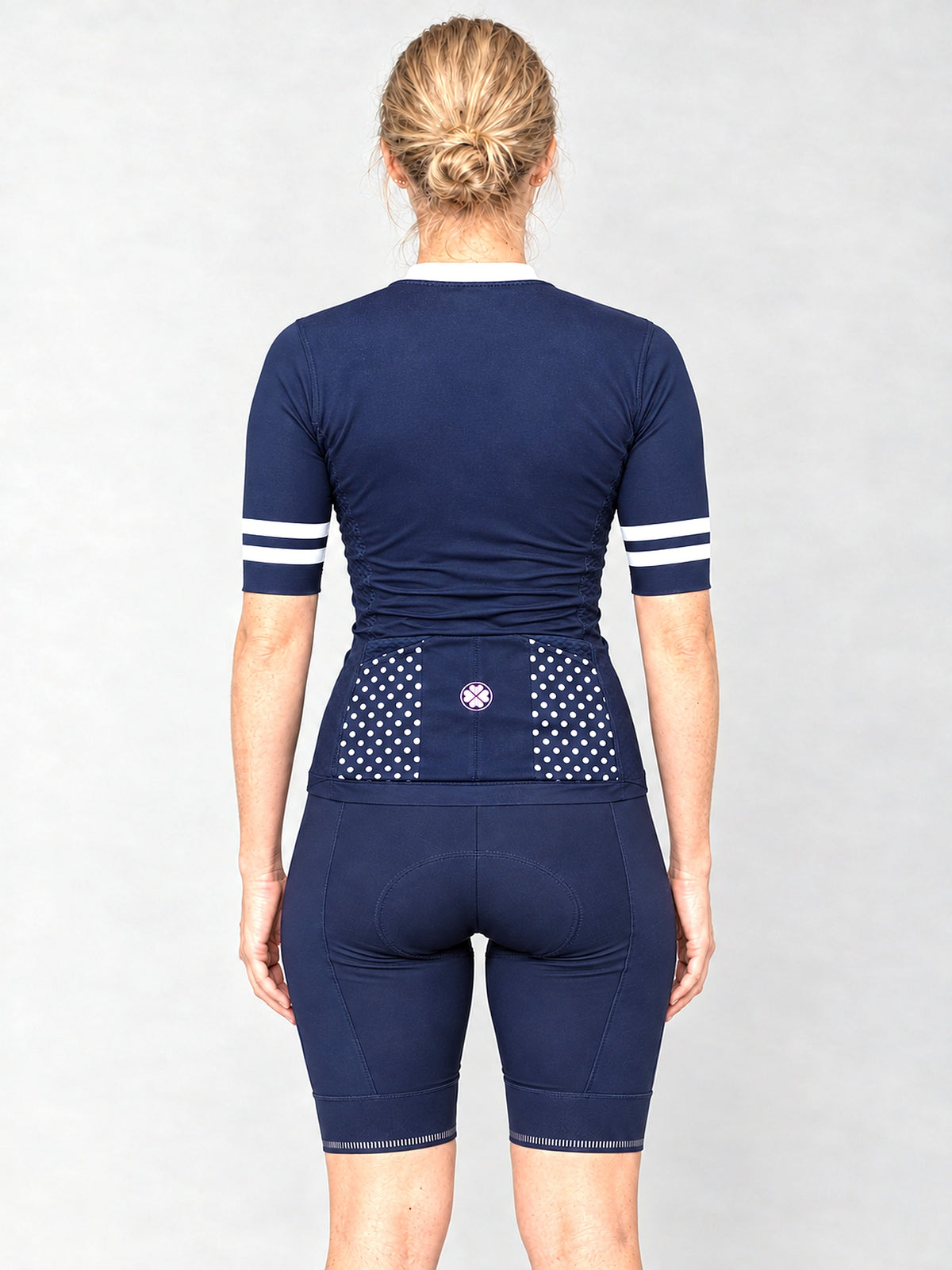 Model wearing The Jackie jersey with navy bib shorts, back view